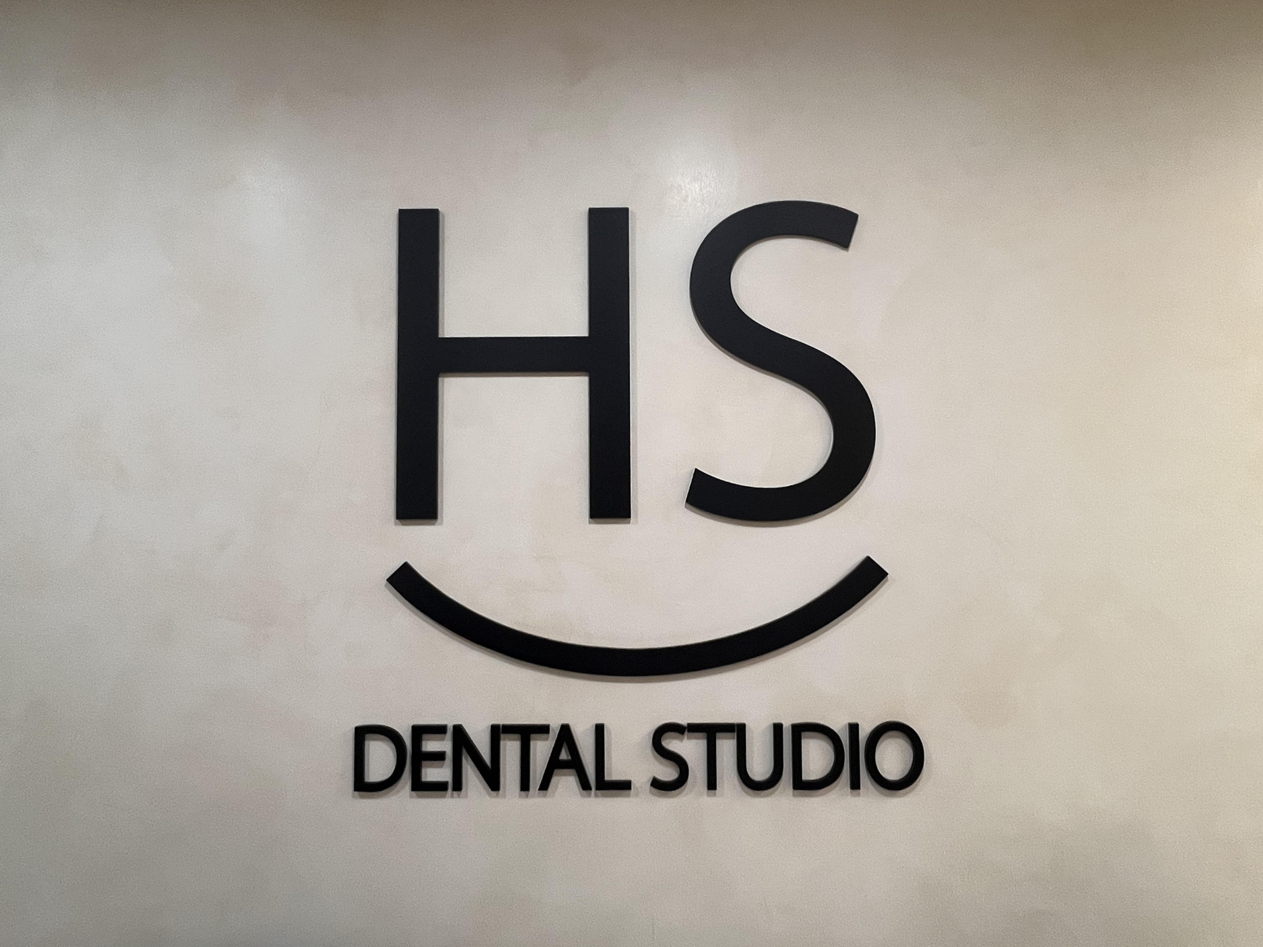 Dr. Rickin Vibhakar dental studio logo on wall with smiley face design